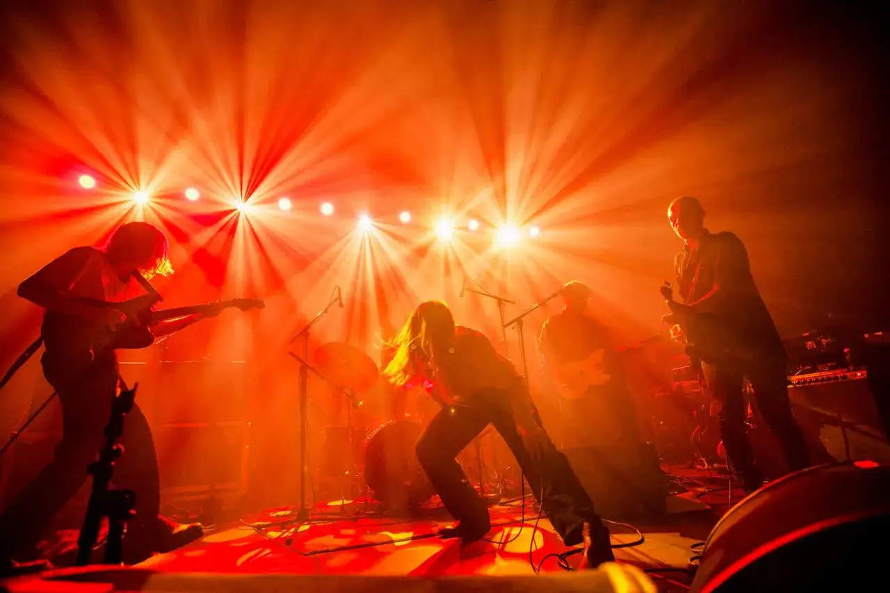 Energetyczny duński zespół rockowy w ogniu świateł scenicznych. Muzycy grają na gitarach, wokalista szaleje na scenie.