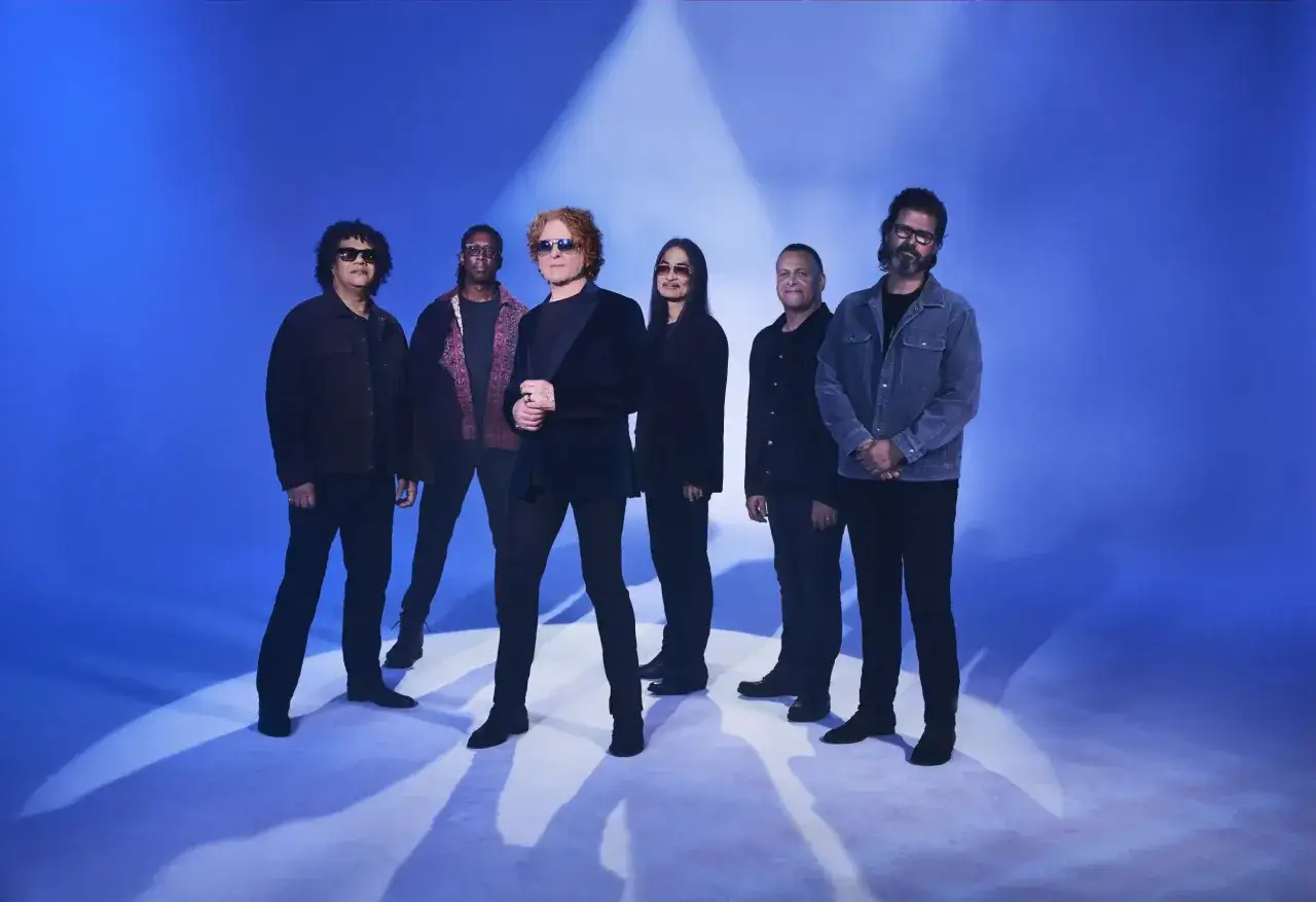 Zesp&oacute;ł Simply Red na tle niebieskiej sceny, gotowy do koncertu.