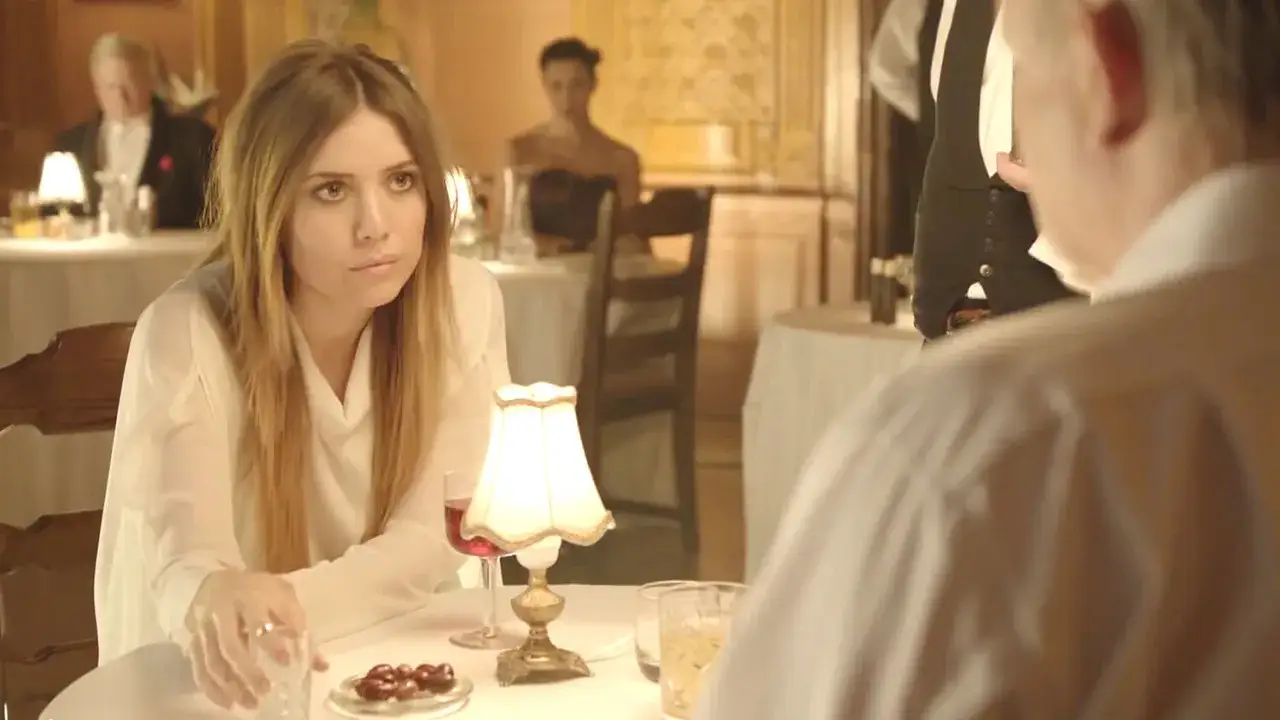 Lykke Li w białej bluzce, zamyślona przy stoliku. Czyżby 