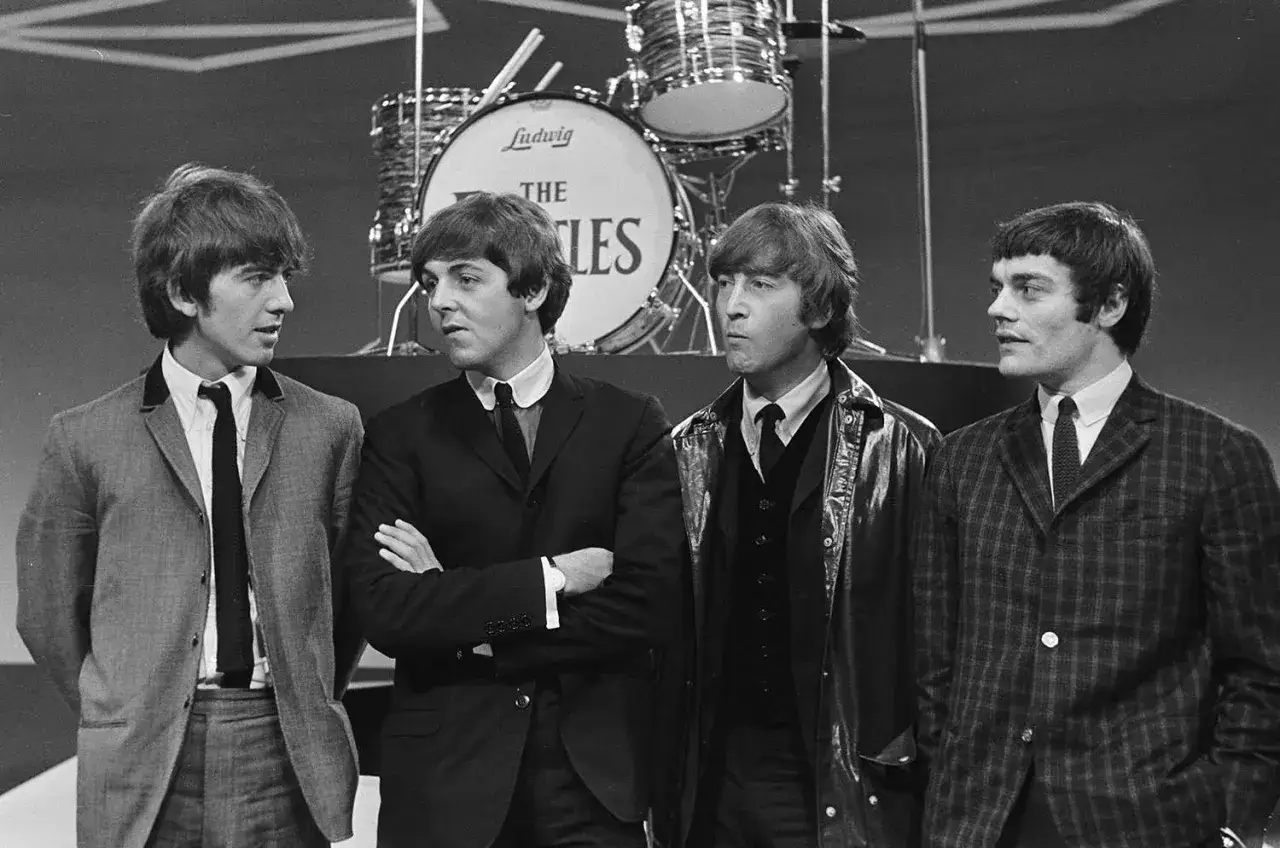 Czterech młodych muzyków, ikony starych zespołów rockowych, pozuje przed perkusją z logo The Beatles.
