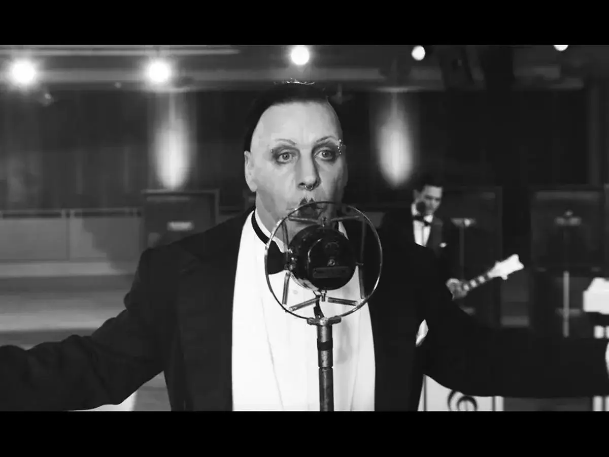 Till Lindemann z Rammstein śpiewa do mikrofonu w stylu retro, jak w teledysku 