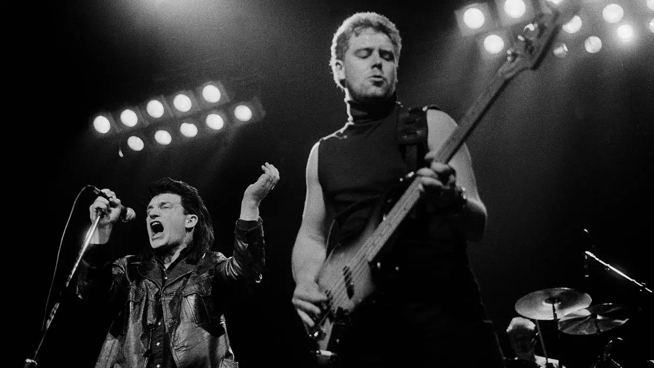 U2 na scenie, Bono śpiewa do mikrofonu, basista gra. Czy to 